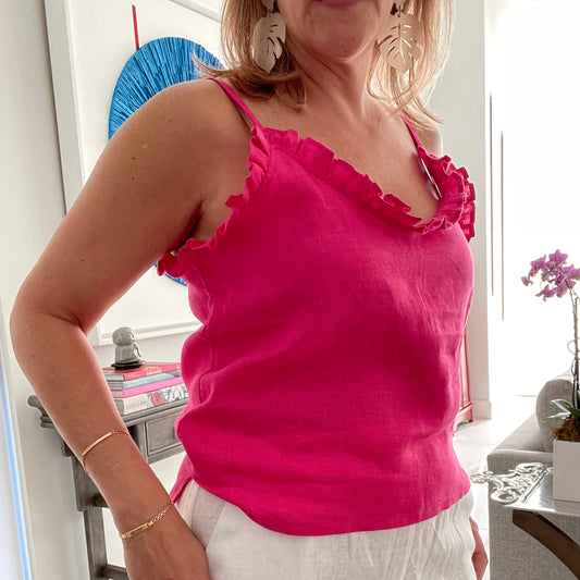 Woman wearing a bright pink frilled tank top in an indoor setting.